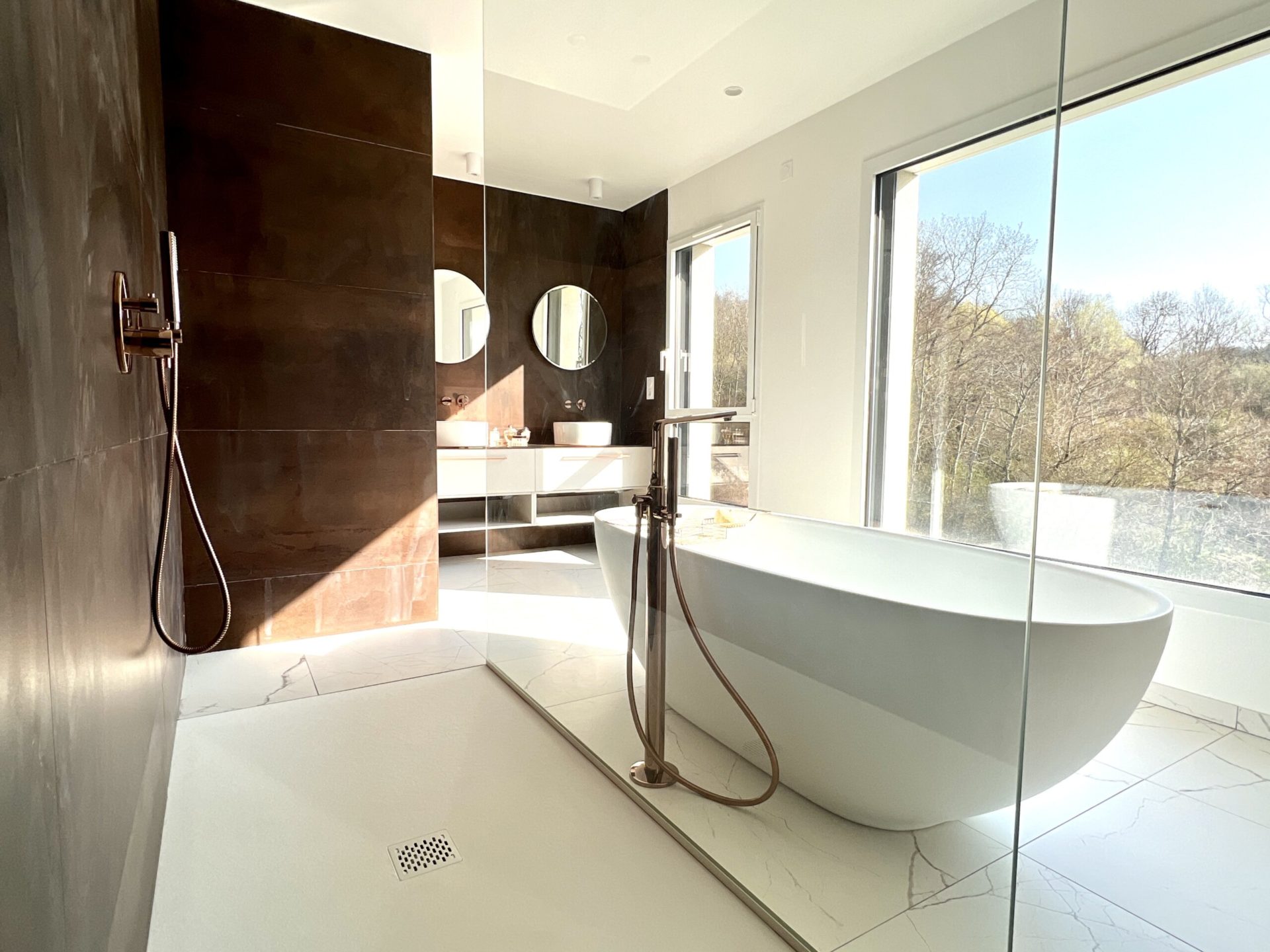 Salle de bain moderne avec baignoire et grande fenêtre.